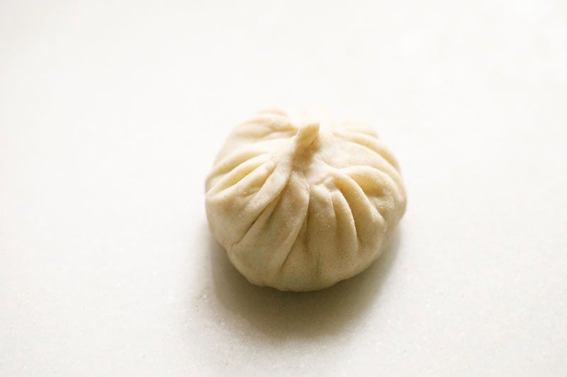 Steamed round dumpling with pleated design.