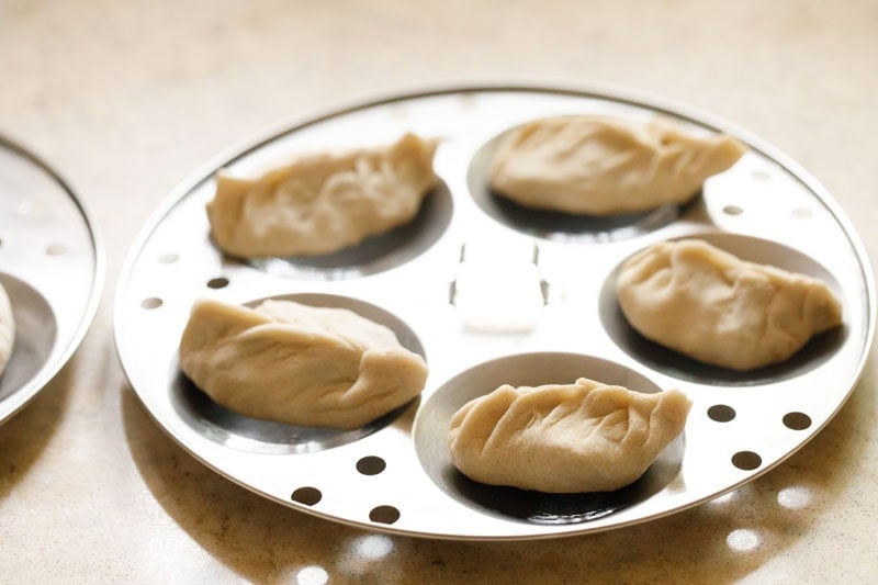 Raw uncooked paneer momos in a steaming tray.