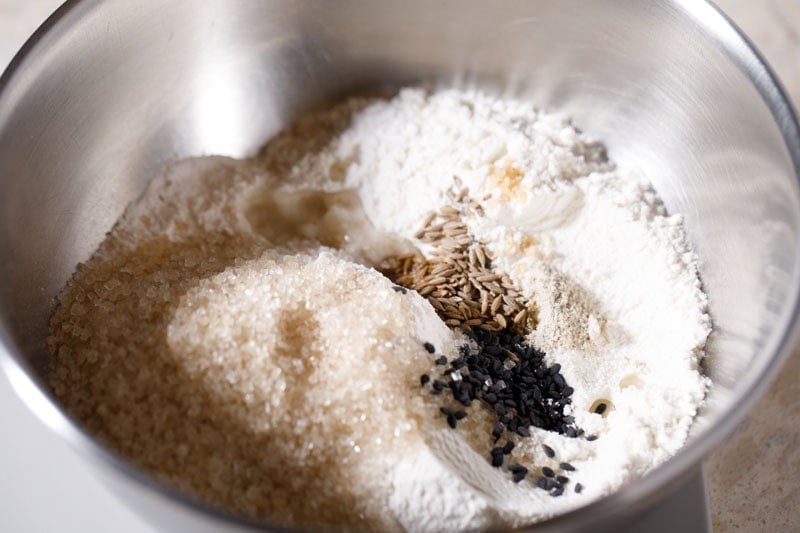 Flours, cumin, black sesame and sugar in a mixing bowl.