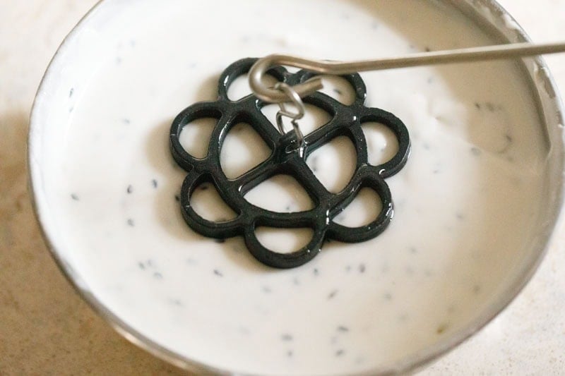 achappam mould dipped in batter.