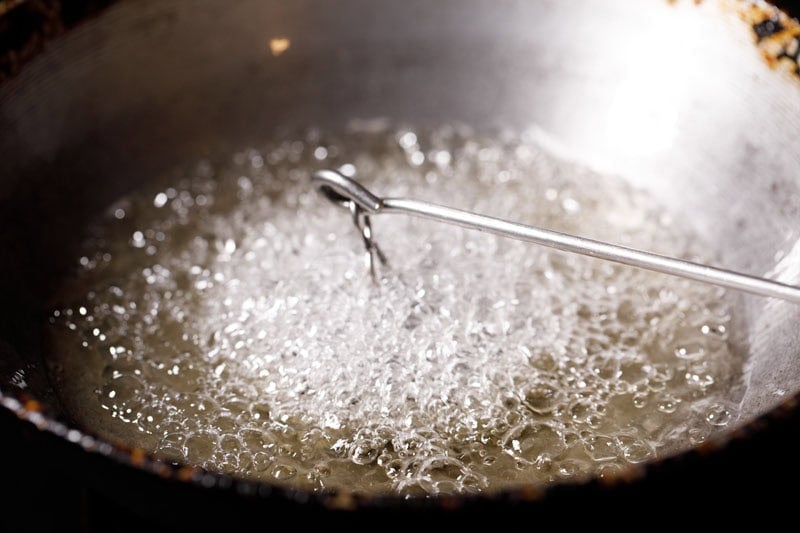 batter coated rose cookie mould in hot oil in kadai.