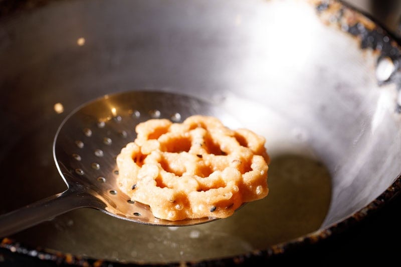 fried achappam or achu murukku on a slotted spoon.