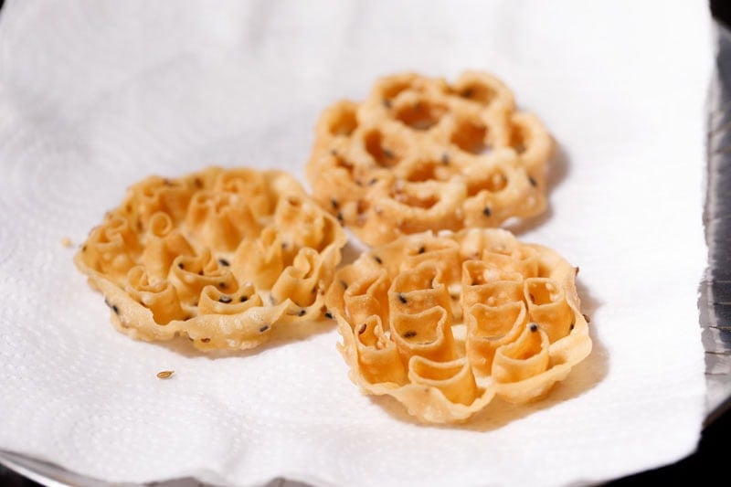 fried rose cookies on kitchen paper towels.