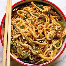 Bowl of stir-fried udon noodles with chopsticks.