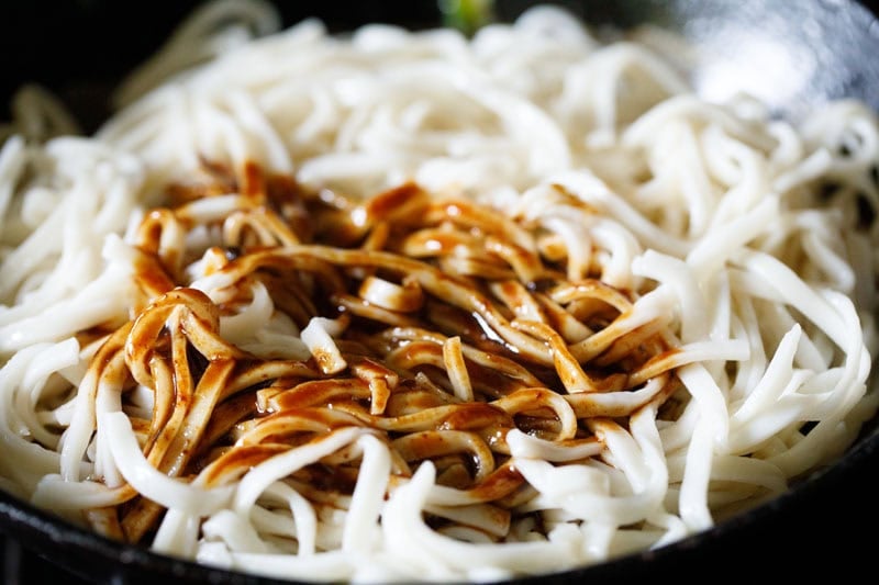 Boiled udon noodles with sauce mix in wok to make yaki udon recipe.