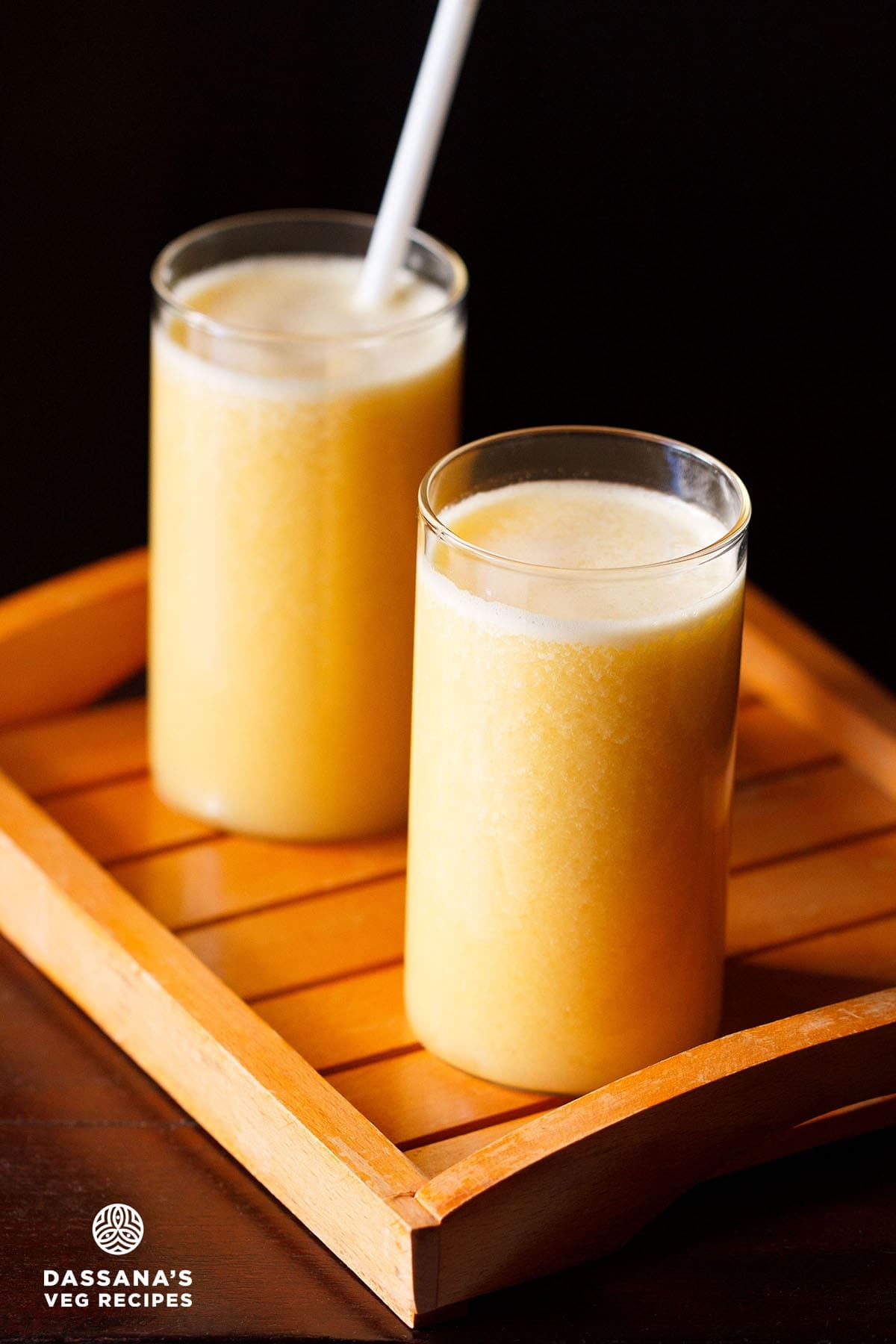 Two glasses of ganga jamuna juice on an orange wooden tray.