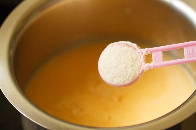 Sugar being added to ganga jamuna juice in pan.