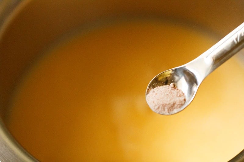 Black salt being added to juice.