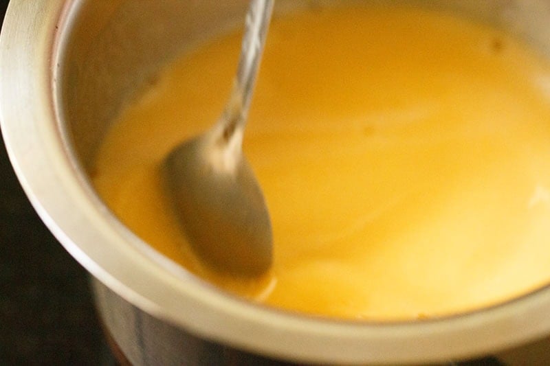 Salt and sugar being mixed with the juice in pan.