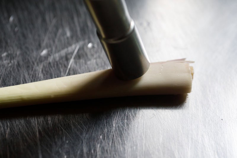 lemongrass stalk being crushed with a pestle.