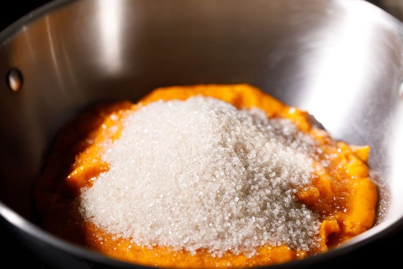Sugar on top of mango puree in a pan.