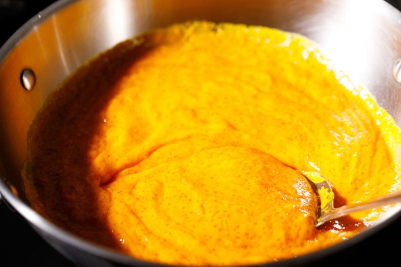 Bright yellow mango puree in pan.