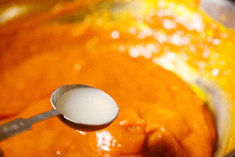 Spoonful of lemon juice over mango jam in pan.