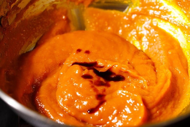 Vanilla extract drizzled on mango jam in pan.