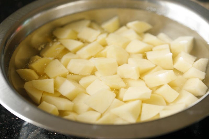 chopped potato cubes soaking in water in bowl.