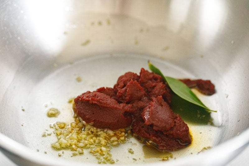 tomato paste and bay leaf in pan.