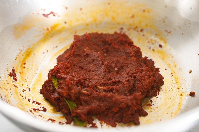 spices and tomato paste mixed in pan.