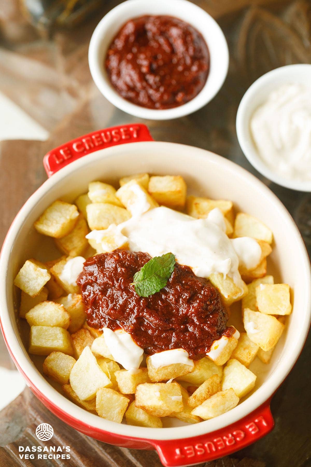 crispy fried potatoes topped with bravas sauce and aioli in a bowl.