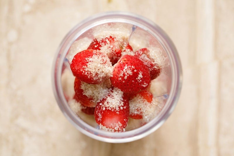 Strawberries and sugar in a blender cup.