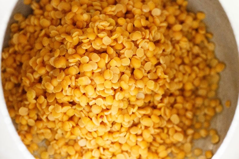 Close-up of rinsed toor dal in a pressure cooker.