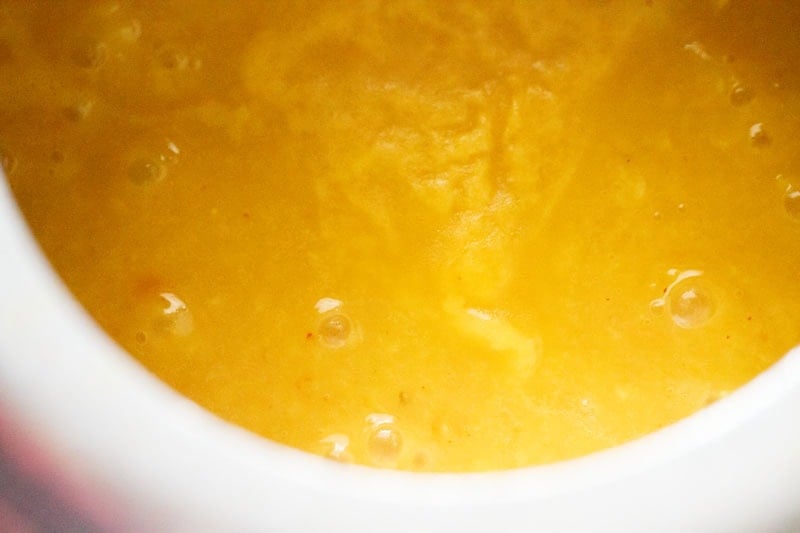 Creamy yellow tur dal simmering in cooker.