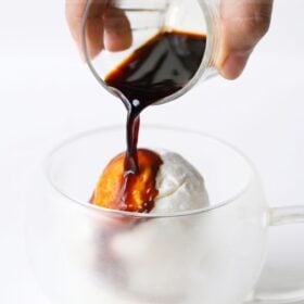 hot espresso being poured over ice cream to prepare affogato recipe.