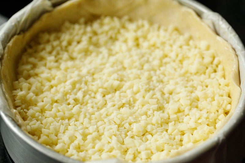 Unbaked pizza crust topped with cheese.