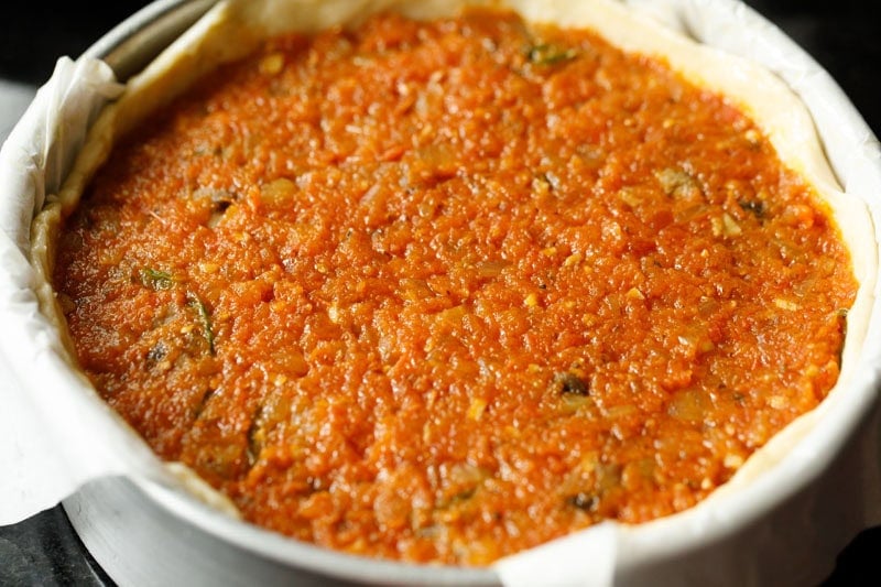Deep dish pizza topped with tomato sauce.