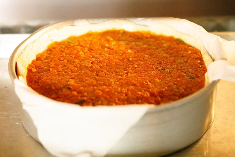 Deep dish pizza baking in oven.