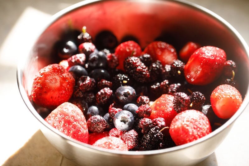 Bowl filled with assorted fresh mixed berries.