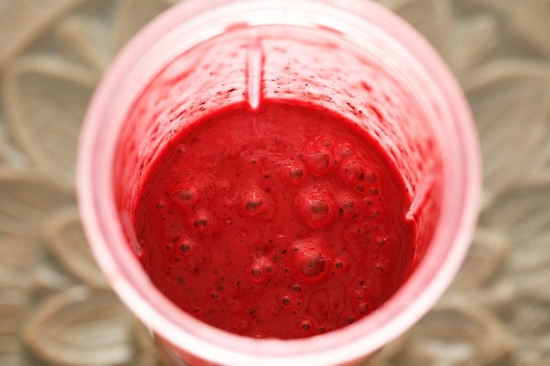 Thick red berry smoothie in blender cup.