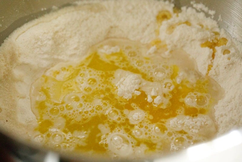 Flour with wet ingredients in a stand mixer bowl.