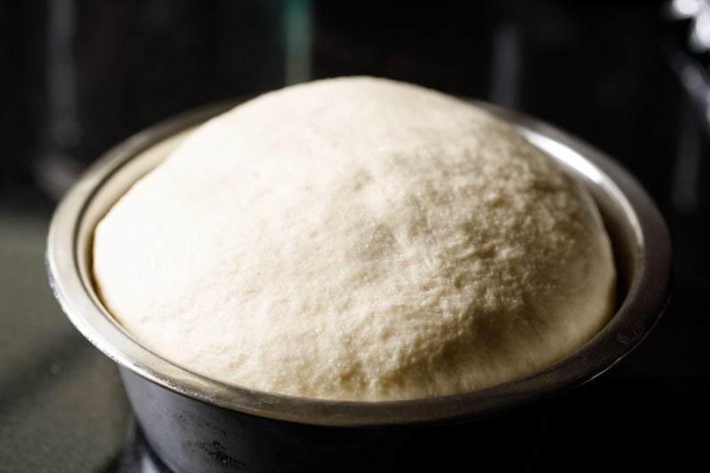 Risen dough in a metal bowl.