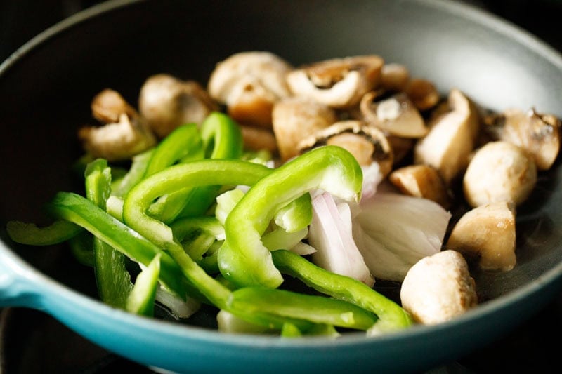 Bell peppers, onions and mushrooms in a skillet.