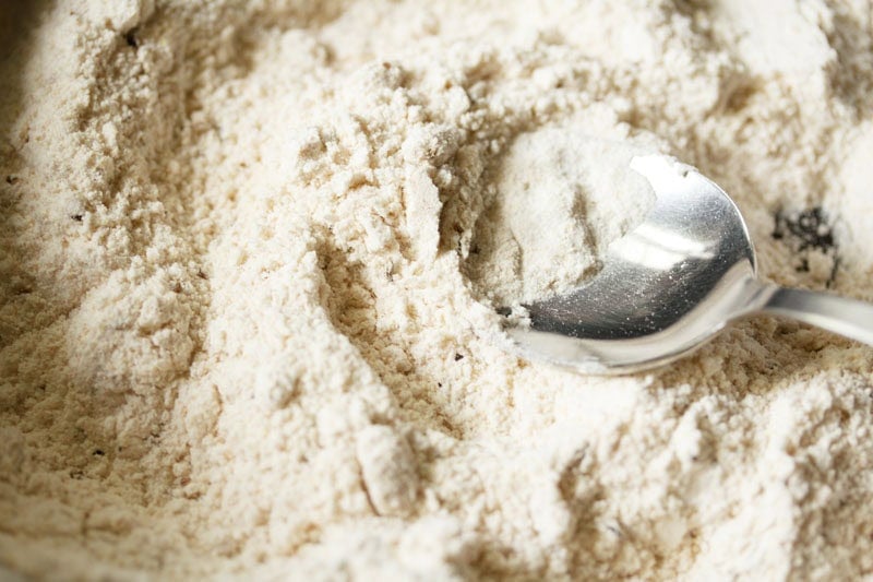 Melted ghee being mixed with flours with a spoon.