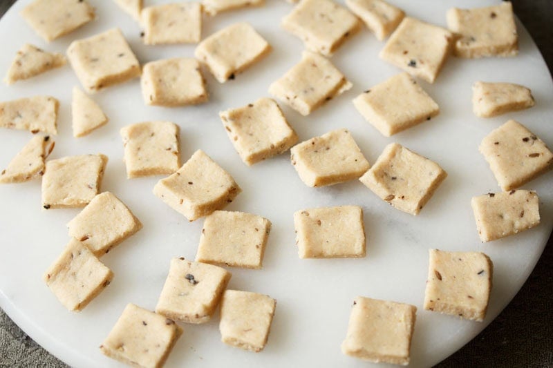 Cut dough biscuits on a white marble board.