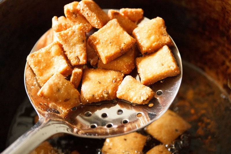 Crispy golden fried diamond cuts in a slotted spoon.