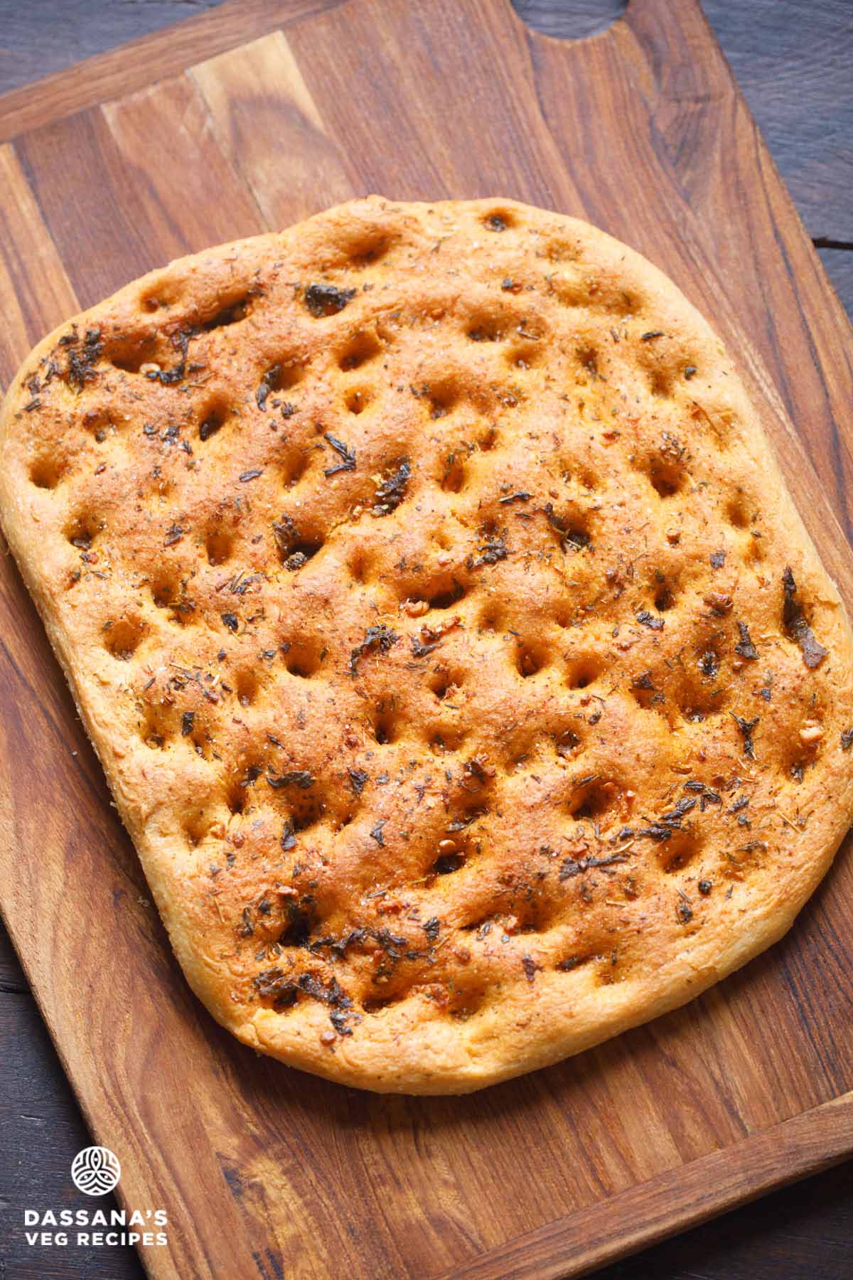Golden-brown focaccia on wooden board.