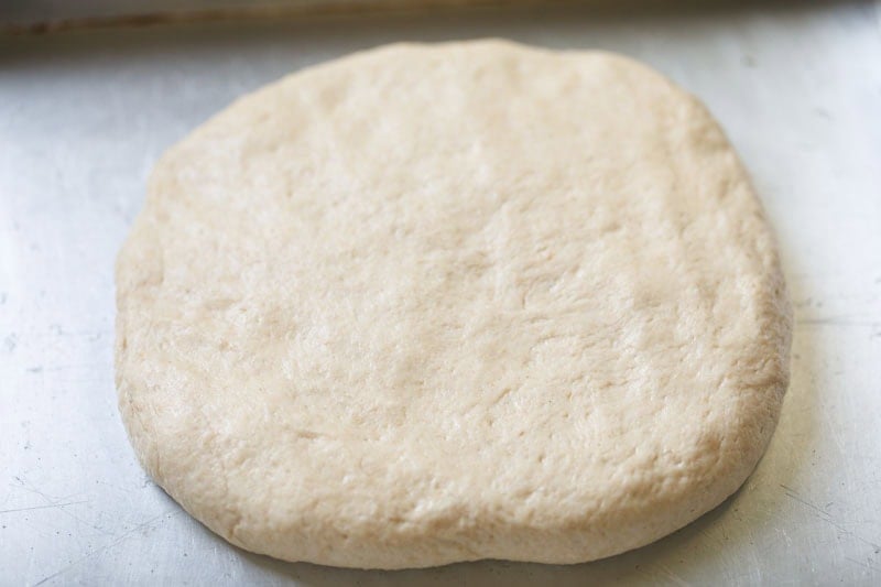 Round, uncooked dough on surface.