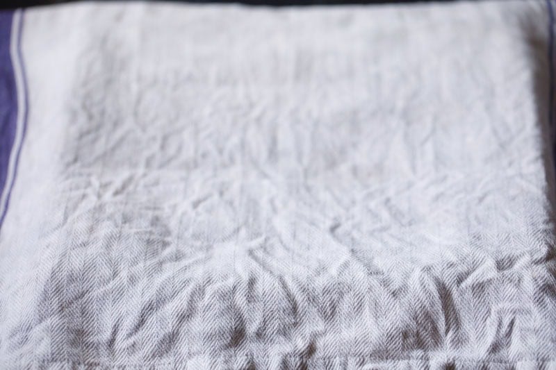 Wrinkled white fabric with purple stripe.