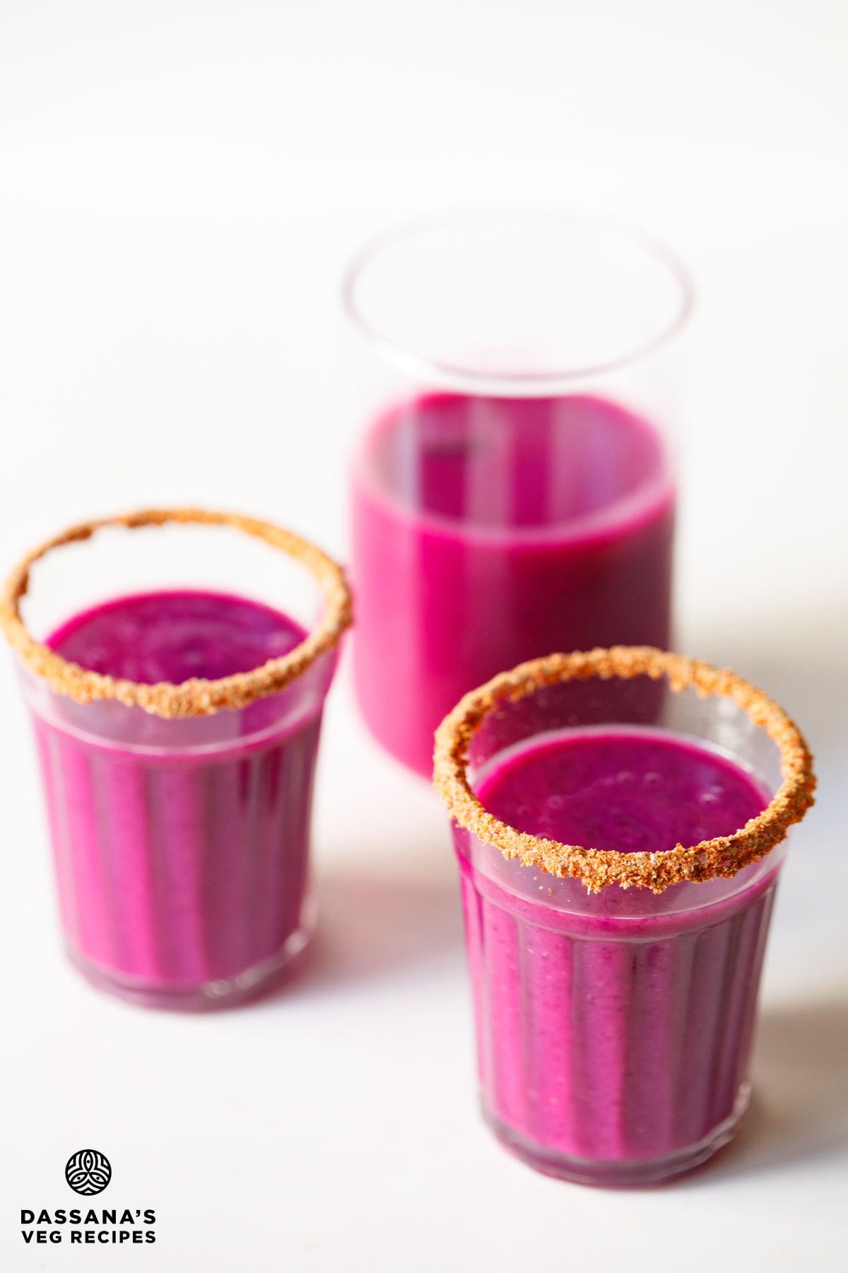 Masala rimmed jamun shots glasses and jamun juice in a glass.