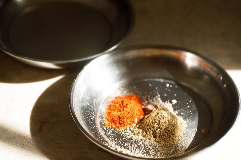 Two small plates each consisting of lemon juice and ground spices and salt.