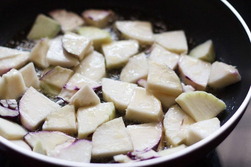 chopped knol khol being pan fried with oil in pan.