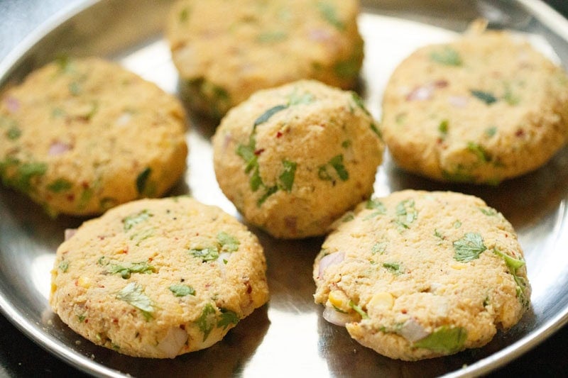Shaped masala vada patties on a steel plate.