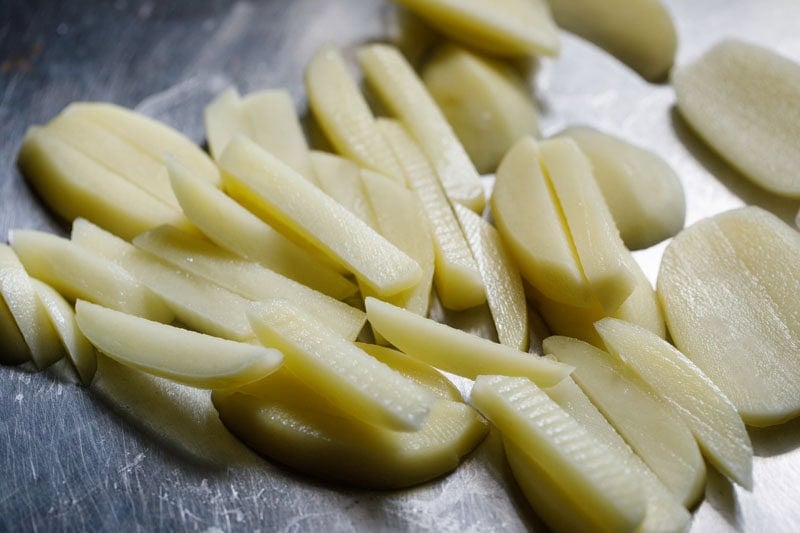 Medium sized potato sticks on chopping board to make peri peri fries.