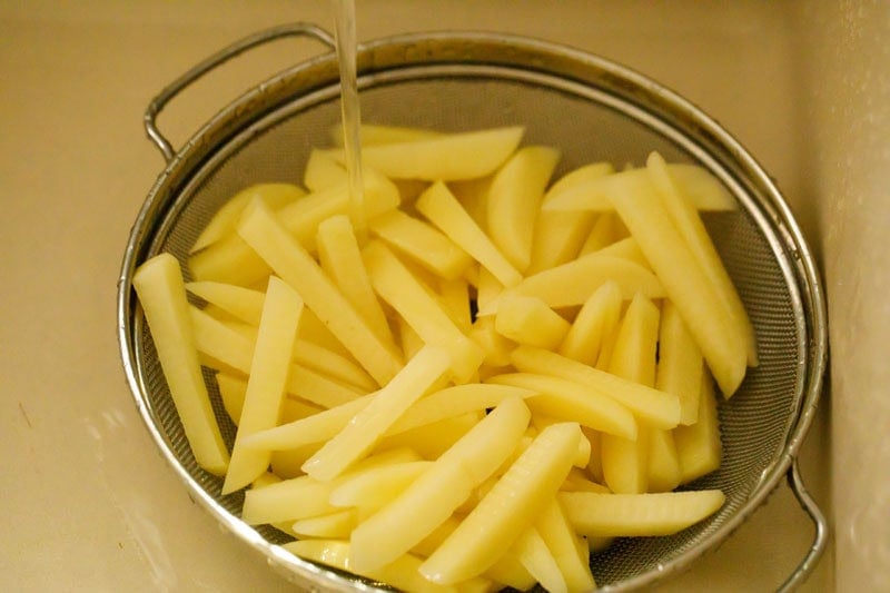 Rinsing potato sticks in strainer.