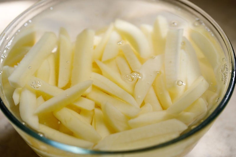 Fries soaking in water in bowl.