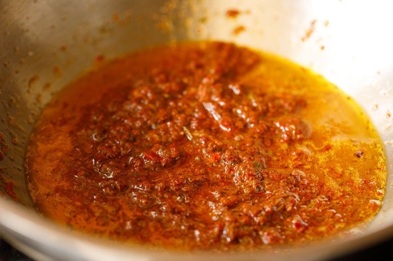 Spicy red curry paste and oil mixture in pan.