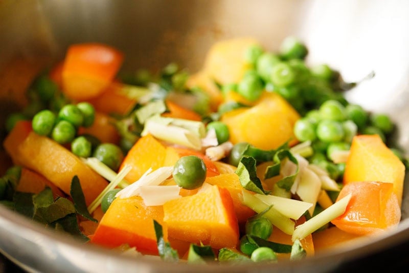 Colorful pumpkin, green peas, thai baby eggplants, lemon grass, kaffir lime leaves in pan.