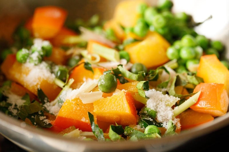 Pumpkin, green peas, thai baby eggplants, lemon grass, kaffir lime leaves with seasonings in pan.